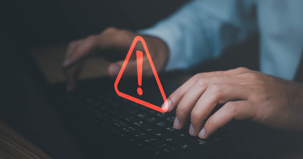 Profesional ante un portátil con un icono de advertencia por incidencia técnica